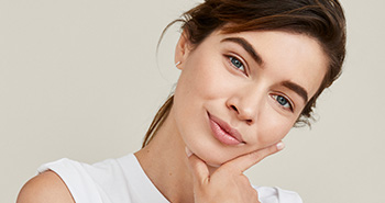 A picture of a smiling redheaded white woman in her twenties with glowing skin
