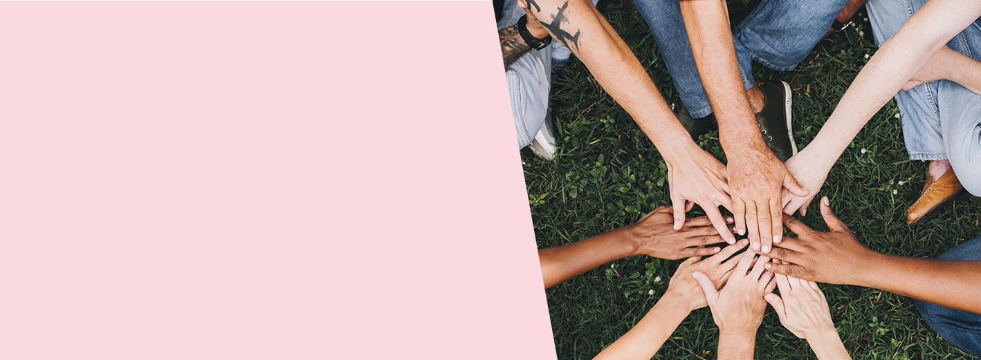 Hands of diverse skin tones join together as a symbol of teamwork.