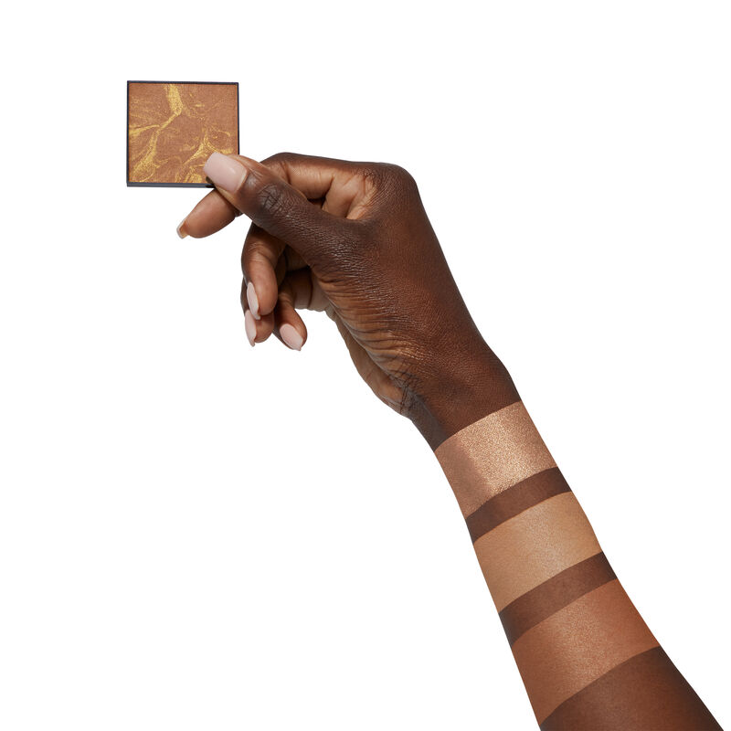 Deep-skinned hand holding limited-edition Mary Kay Illuminating Bronzer