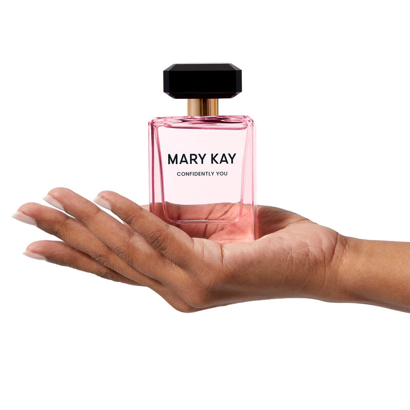 The light pink Mary Kay Confidently You bottle is held heroically by a hand