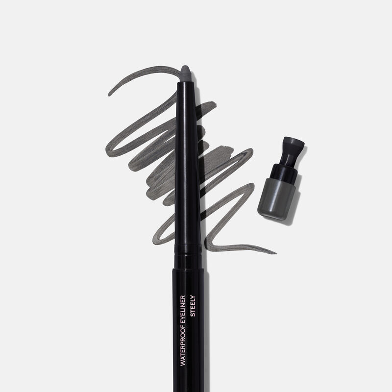 Uncapped Mary Kay Waterproof Eyeliner in Steely against product rub next to sharpener cap