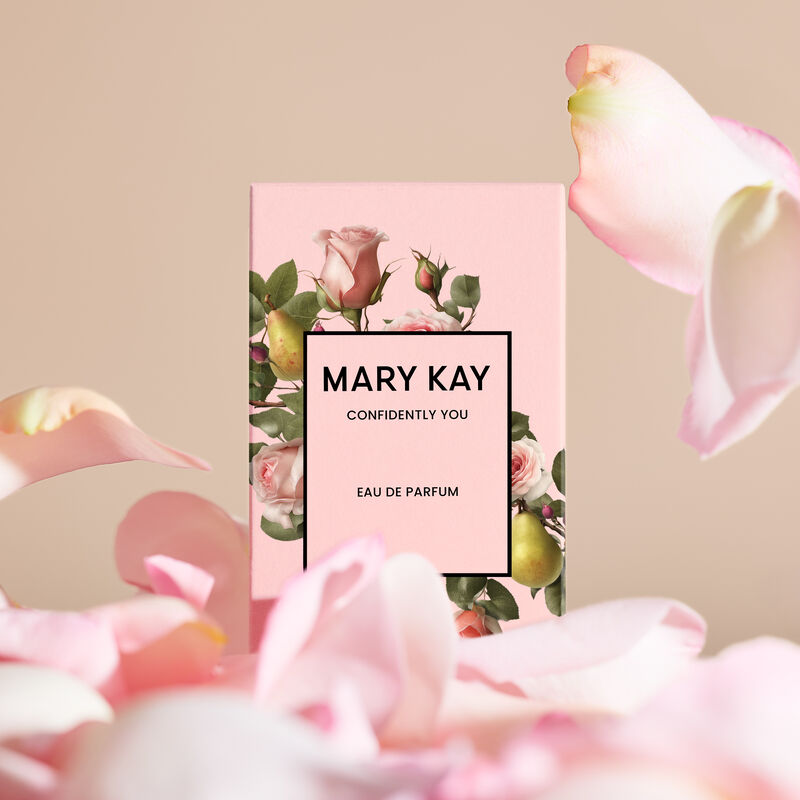 The Mary Kay Confidently You light pink box with roses and pears on it appears surrounded by falling petals