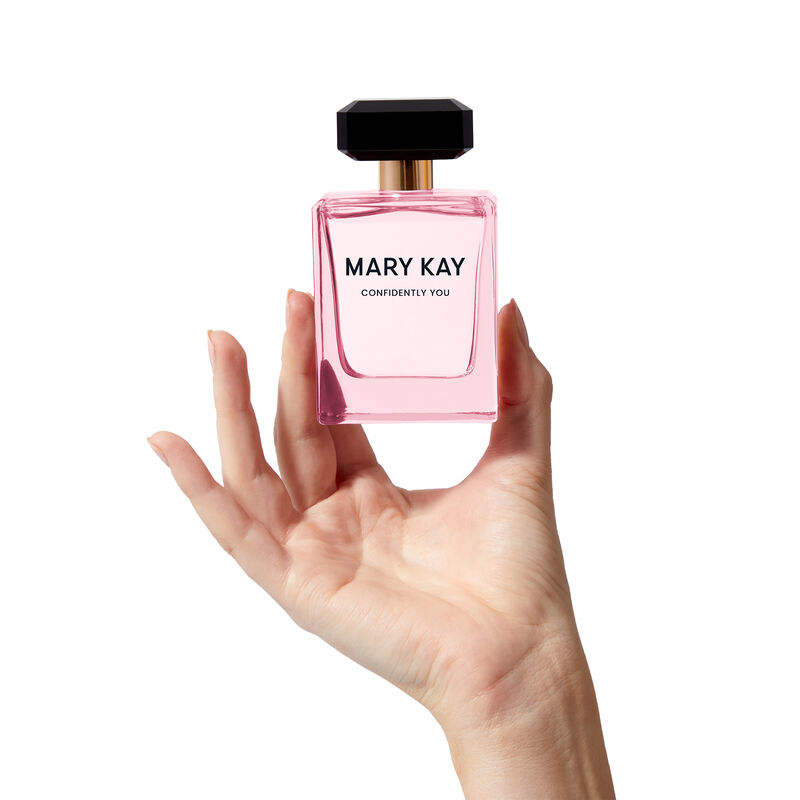 The light pink Mary Kay Confidently You bottle is held heroically by a hand