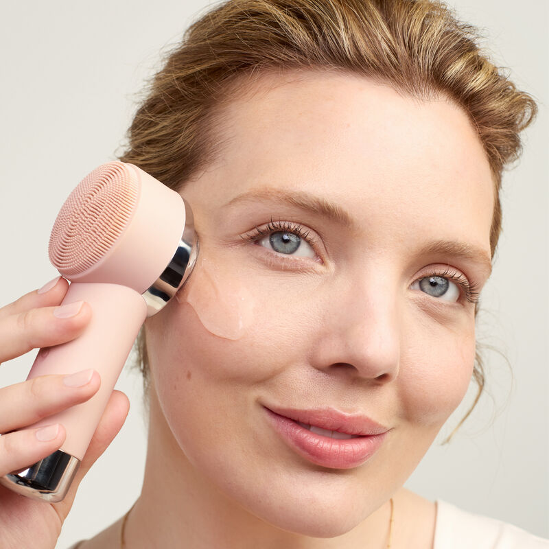 Modelo usando la funcion termal del Skinvigorate Duo mientras aplica un producto en su rostro