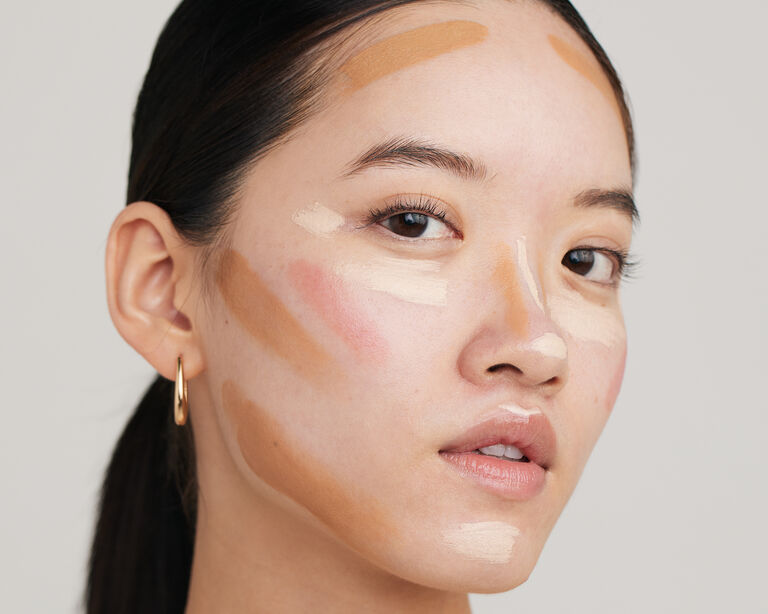 Mujer con productos de maquillaje sobre el rostro