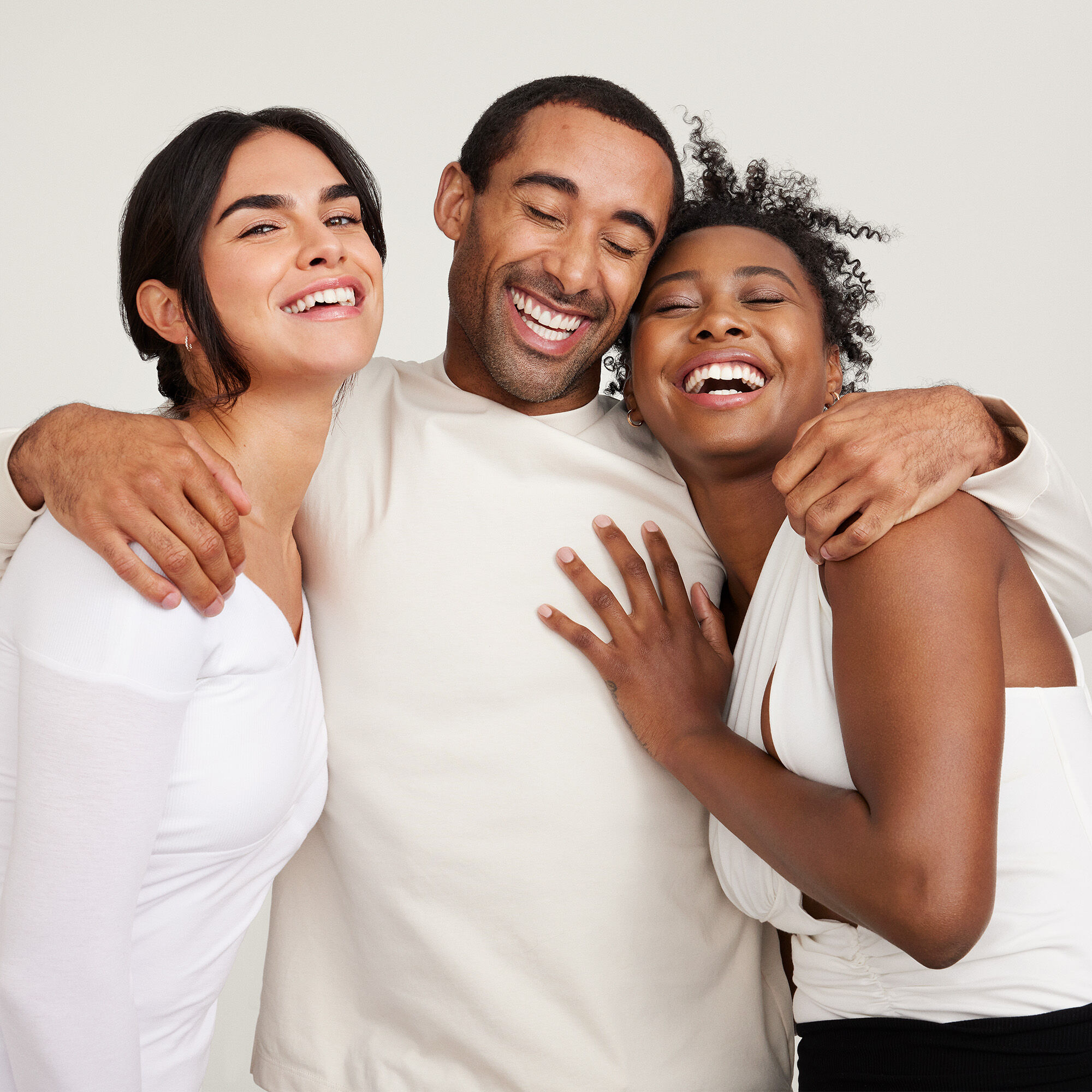 Tres personas abrazadas y sonriendo