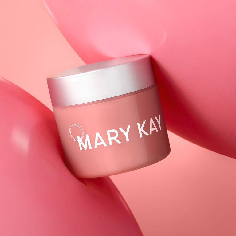 Profile view of woman with fun earrings and hairclips applying Mary Kay Unlimited Lip Gloss 