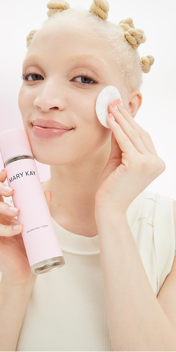Modelo rubia aplicando el T&oacute;nico Equilibrante Mary Kay&reg; en la mejilla